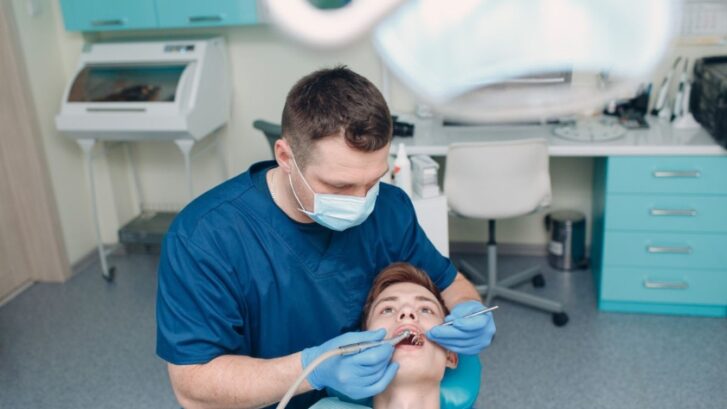 Dentist examining young patient's teeth in modern dental office in Snellville, GA.