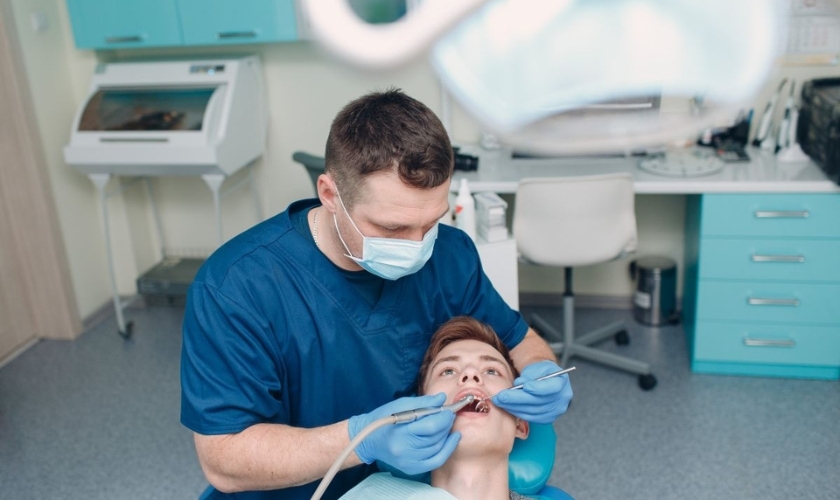 Dentist examining young patient's teeth in modern dental office in Snellville, GA.