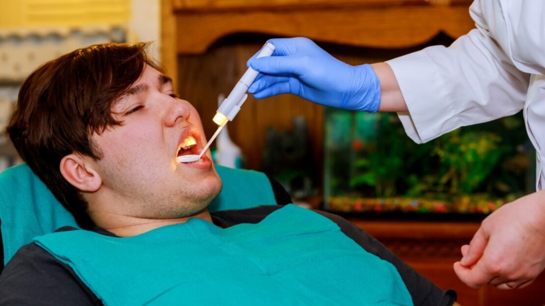 Dentist examining patient's teeth during oral checkup to monitor dental health and prevent fluorosis.