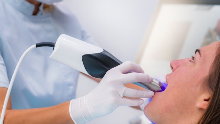 Dentist performing ultrasonic scaling treatment on patient's jaw during full-mouth reconstruction in Snellville.