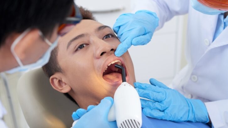 Young patient receiving dental examination with intraoral scanner during bite assessment.