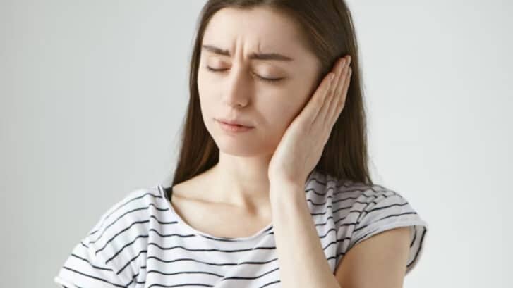 Woman holding her cheek in discomfort after tooth extraction in Snellville, GA.