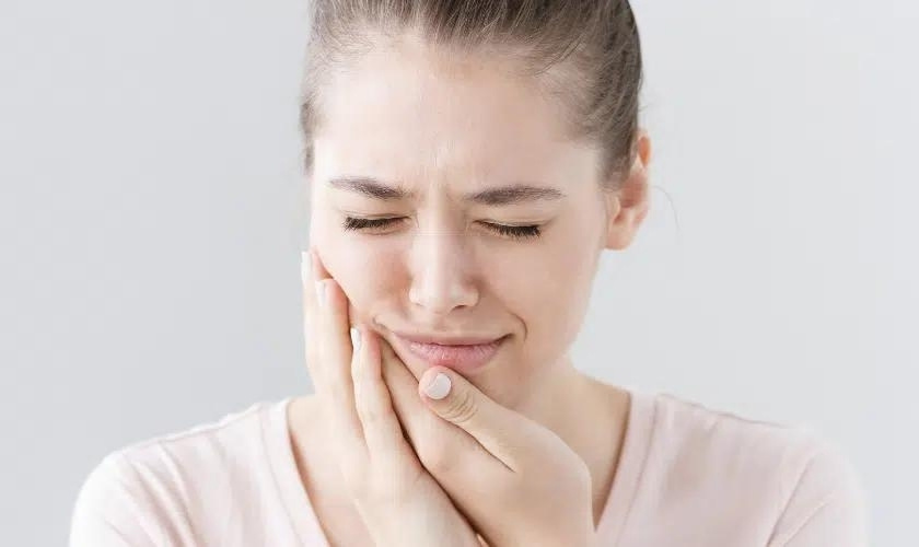 Woman experiencing jaw pain, holding her face in discomfort after root canal treatment.