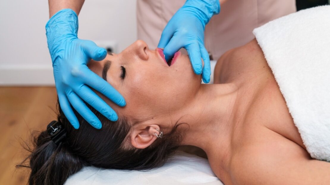 Dentist examining patient's jaw and facial structure during TMJ assessment in Snellville.