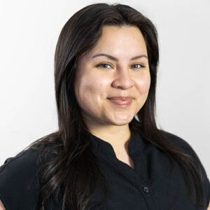 Professional headshot of woman with long dark hair wearing black shirt against white background.