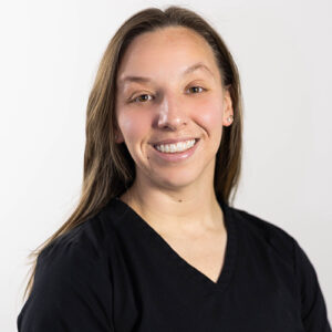 Woman smiling at camera wearing black shirt against white background, professional headshot.