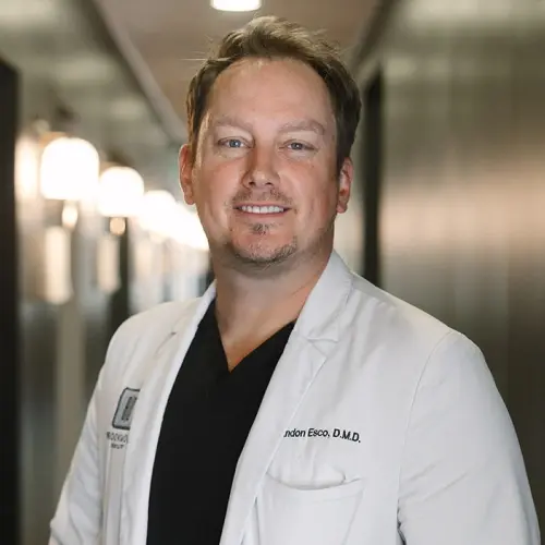 Dr. Brandon Esco, D.M.D. portrait in white coat at Snellville dental practice.
