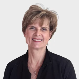 Professional headshot of a smiling woman in dark business attire against neutral background.