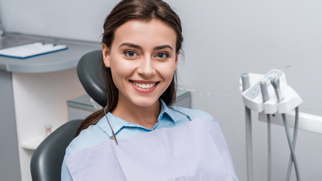 Smiling female patient wearing dental bib in treatment room at Snellville dental practice.